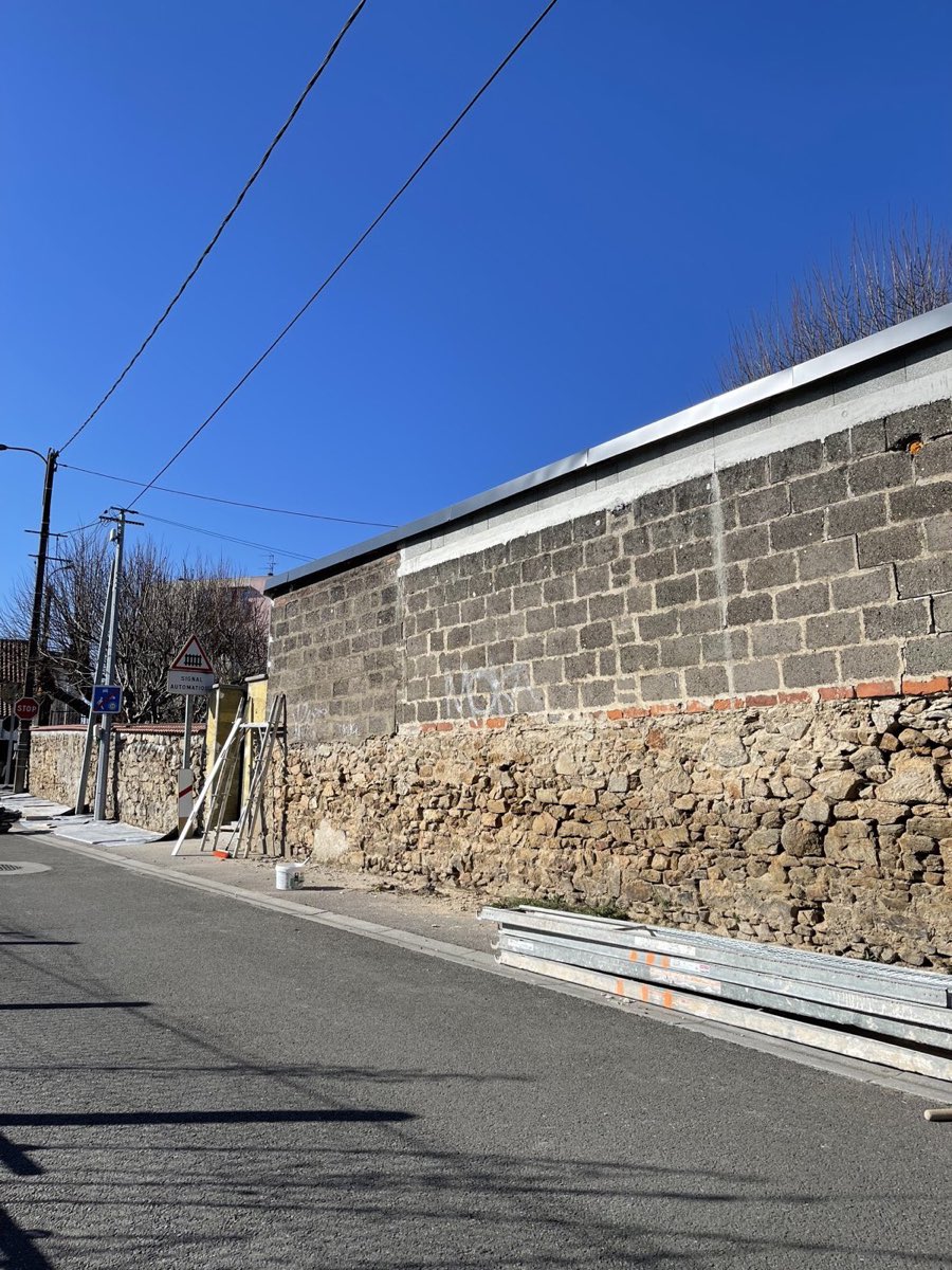 Mur de clôture en parpaings bruts et pierre, taggé, avant travaux d'enduit par REIS façade