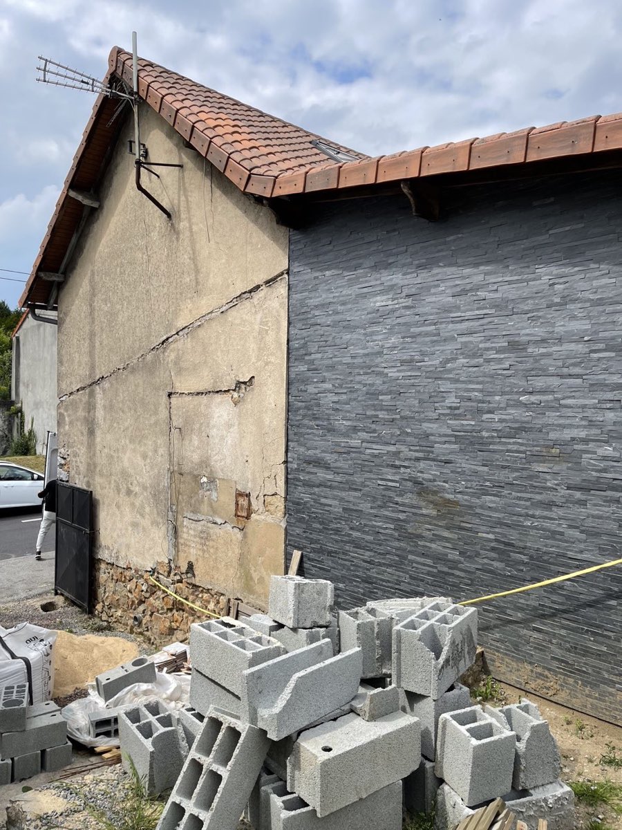 Pignon de maison à l'enduit ancien dégradé et fissuré, avant reprise