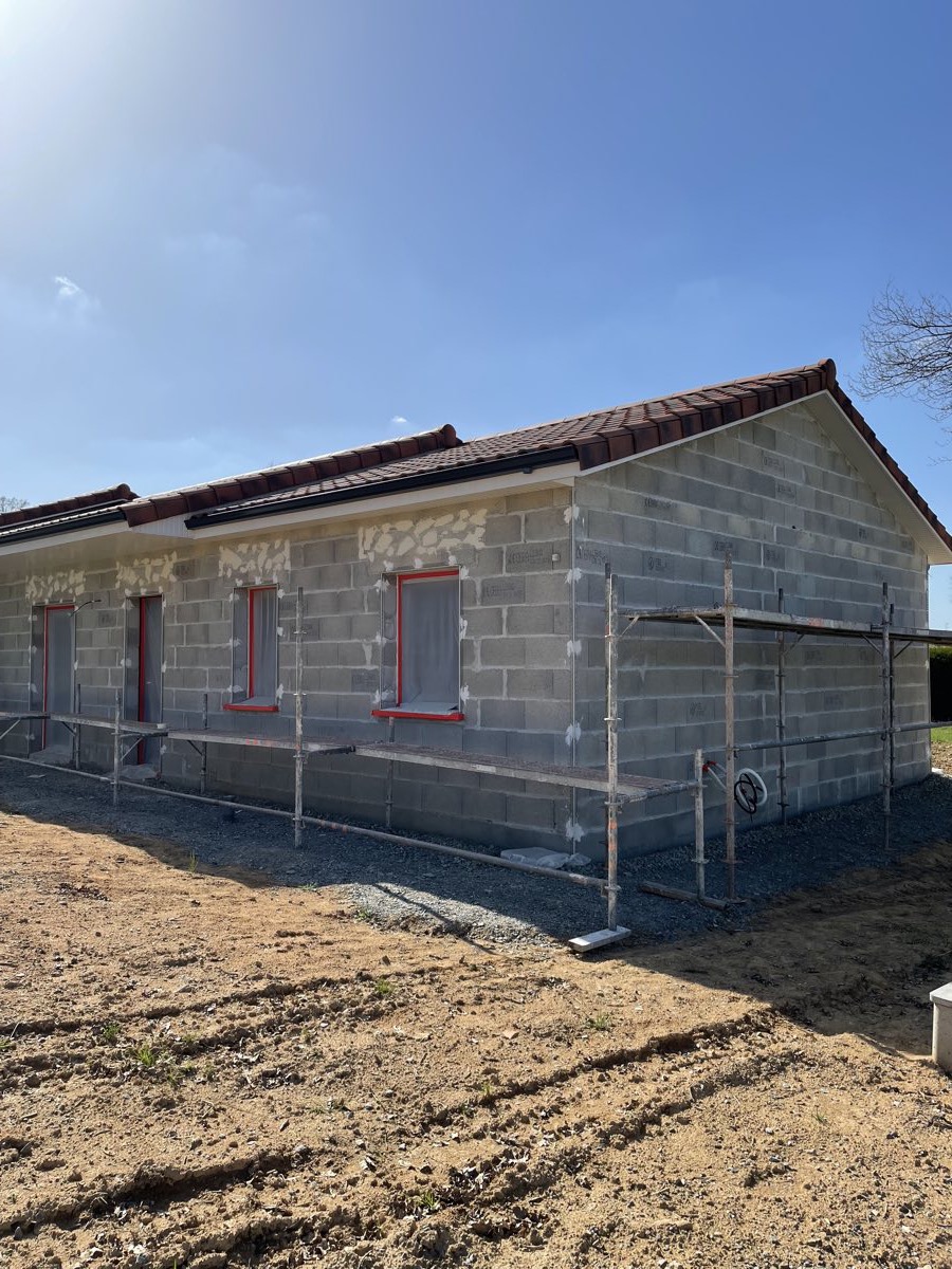 Maison neuve de plain-pied en parpaings sous échafaudage, avant enduit de façade par REIS façade