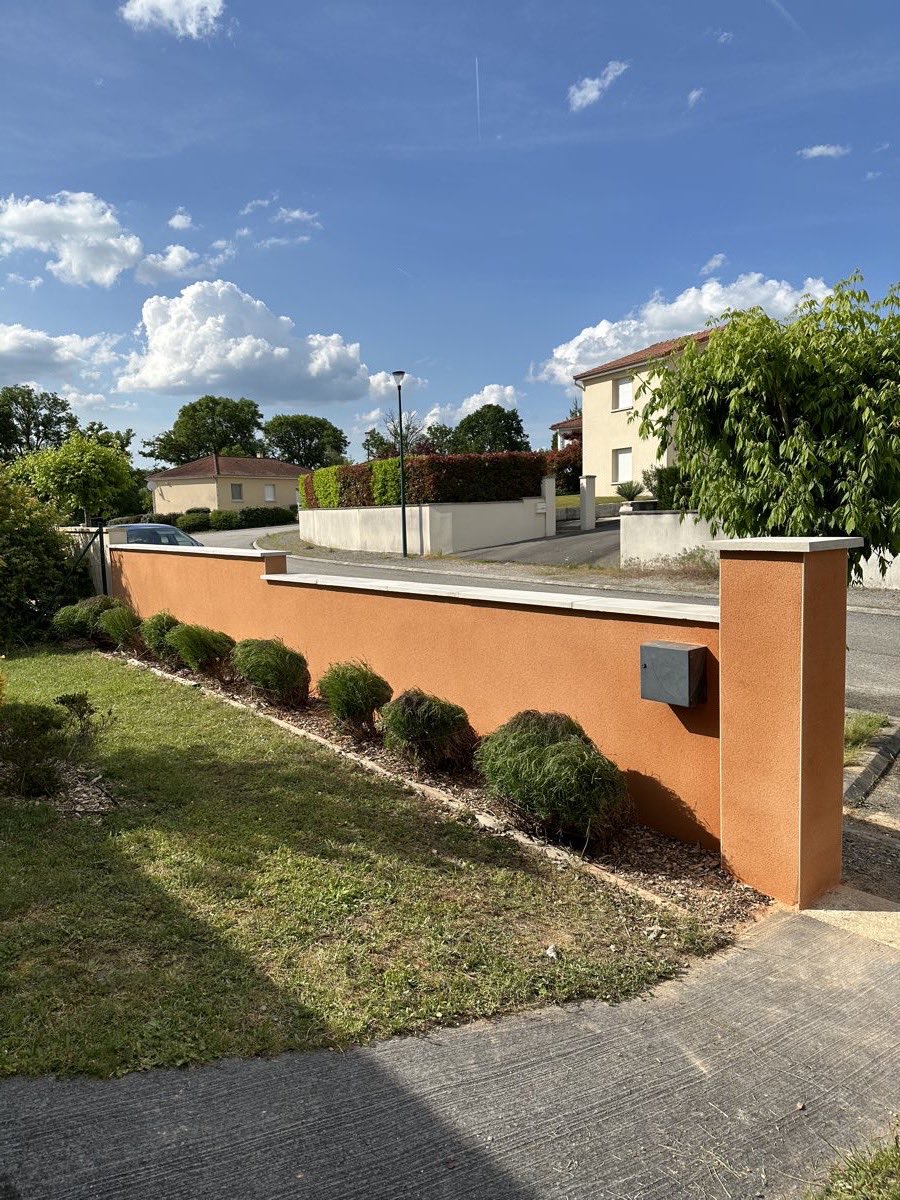 Le même mur de clôture après enduit ocre et pose d'un couvre-mur, réalisé par REIS façade