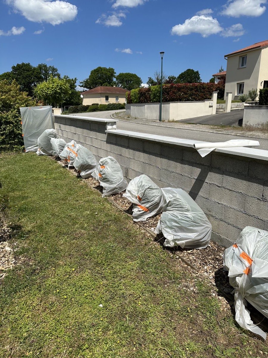 Mur de clôture de jardin en parpaings bruts protégés par des bâches, avant enduit