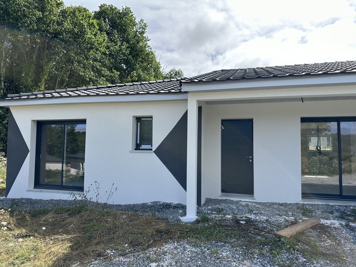 Façade de maison contemporaine à enduit blanc rehaussé de motifs triangulaires anthracite