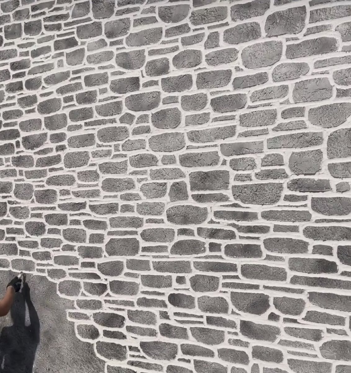 Gros plan sur un enduit imitation pierre gris sculpté à la main, joints blancs marqués